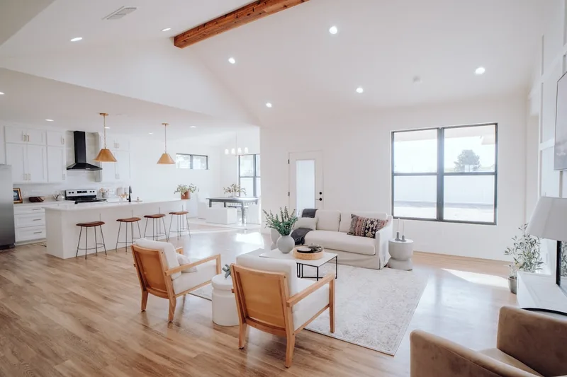 A bright minimalist living room with clean empty surfaces, a single green plant on a shelf, and soft natural light through a large window